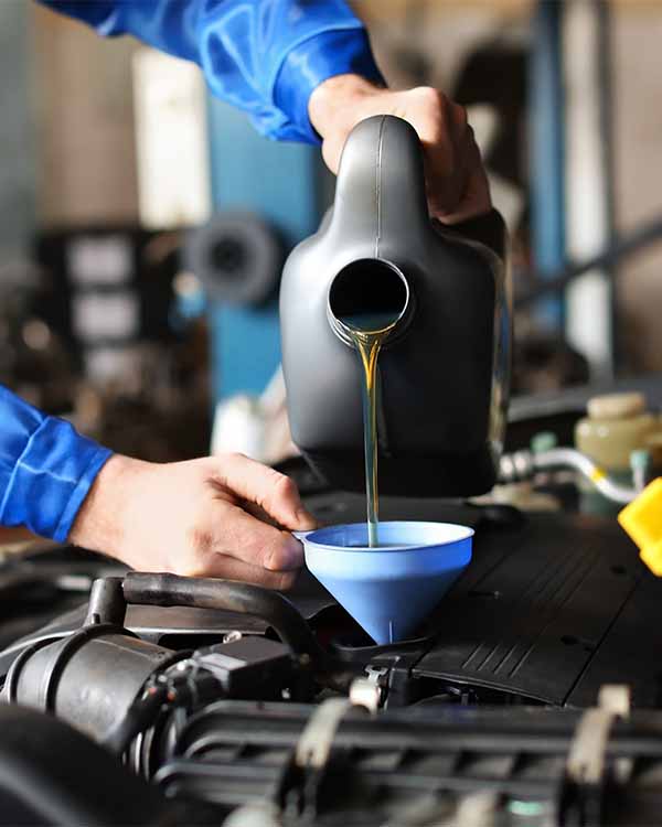 Car mechanic filling oil